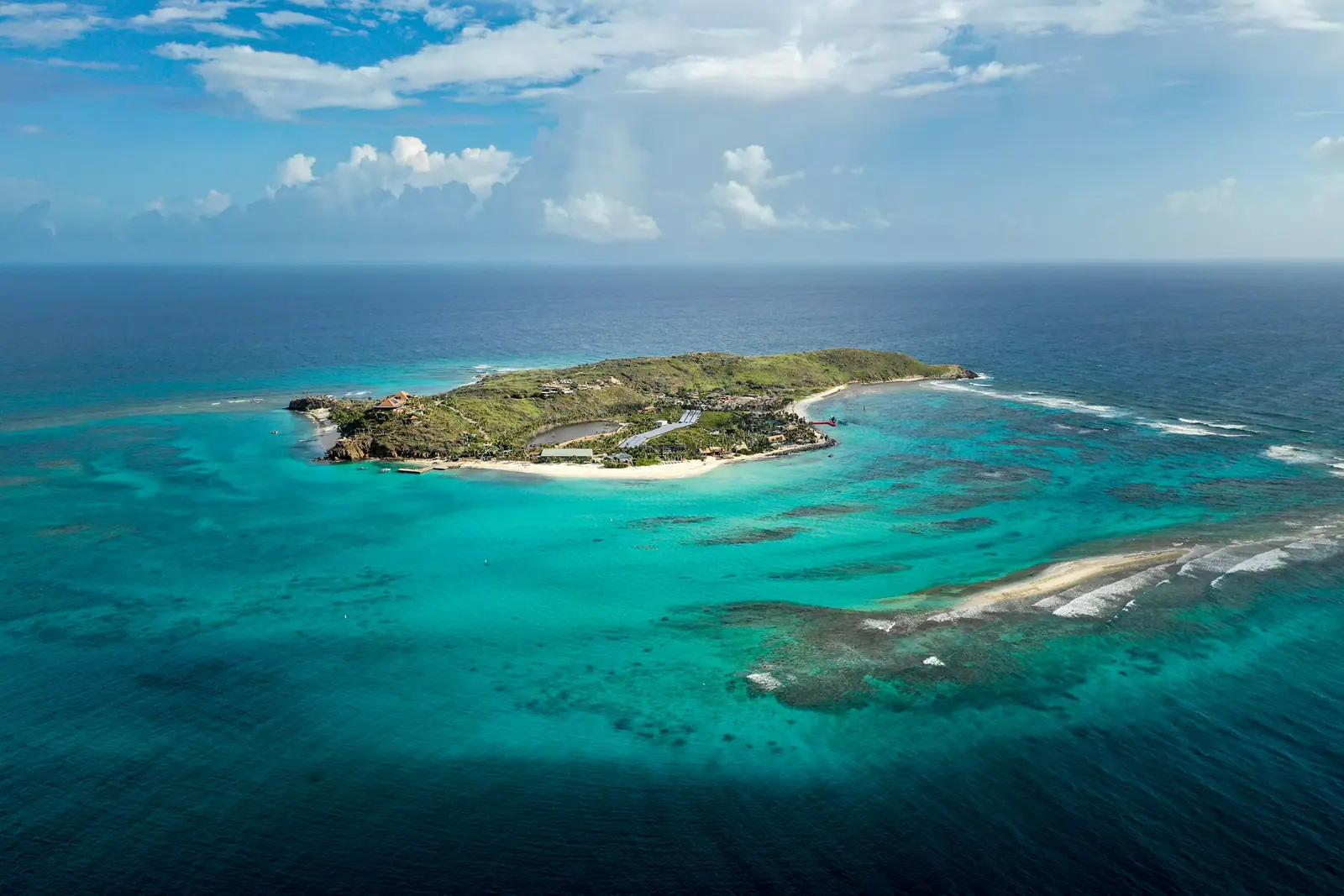 Aerial view of a small green island ringed by turquoise reef water in the British Virgin Islands